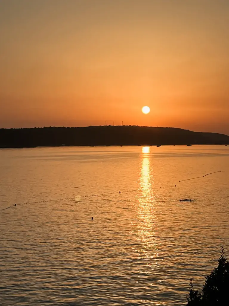 Sonnenuntergang an der kroatischen Küste. Der Himmel ist orange und die Sonne geht gleich unter