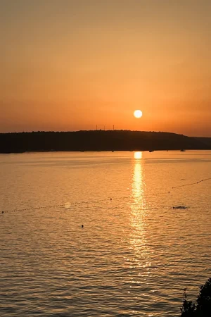 Sonnenuntergang an der kroatischen Küste. Der Himmel ist orange und die Sonne geht gleich unter